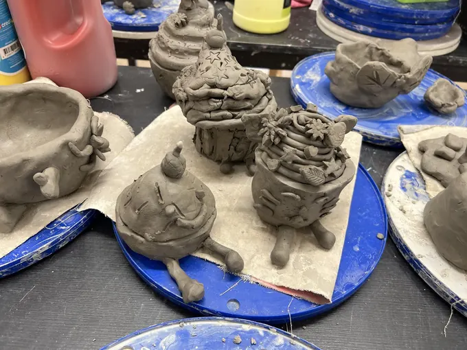Hand-built clay pots and sculptures on boards in the studio