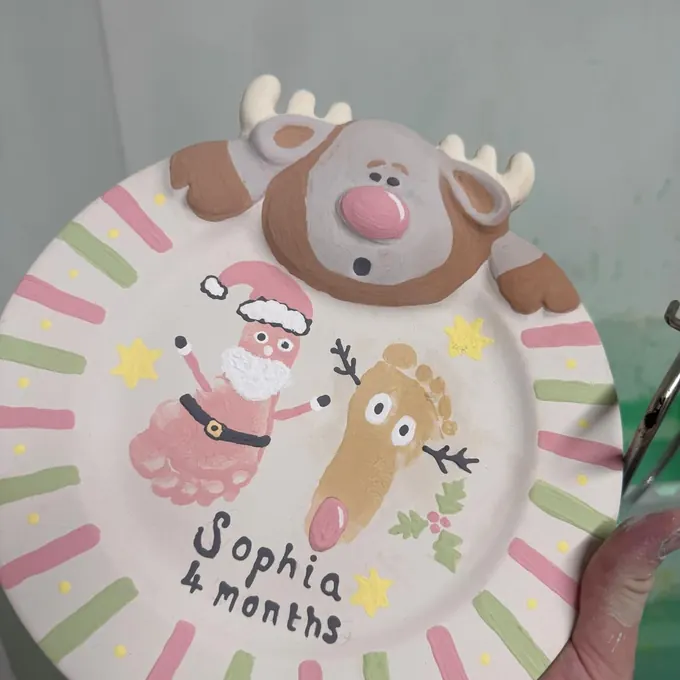 A Christmas keepsake plate with a baby’s footprints painted as Santa and a reindeer, named Sophia, 4 months