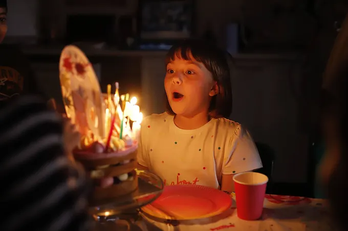 A child blowing out birthday candles at a Pictura party