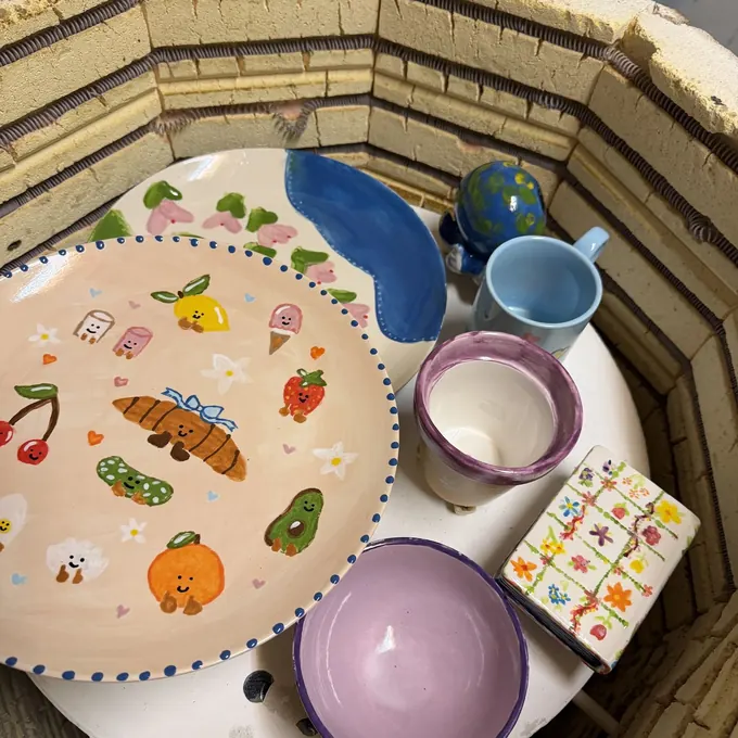 A kiln load of fired pottery, including a plate painted with food illustrations