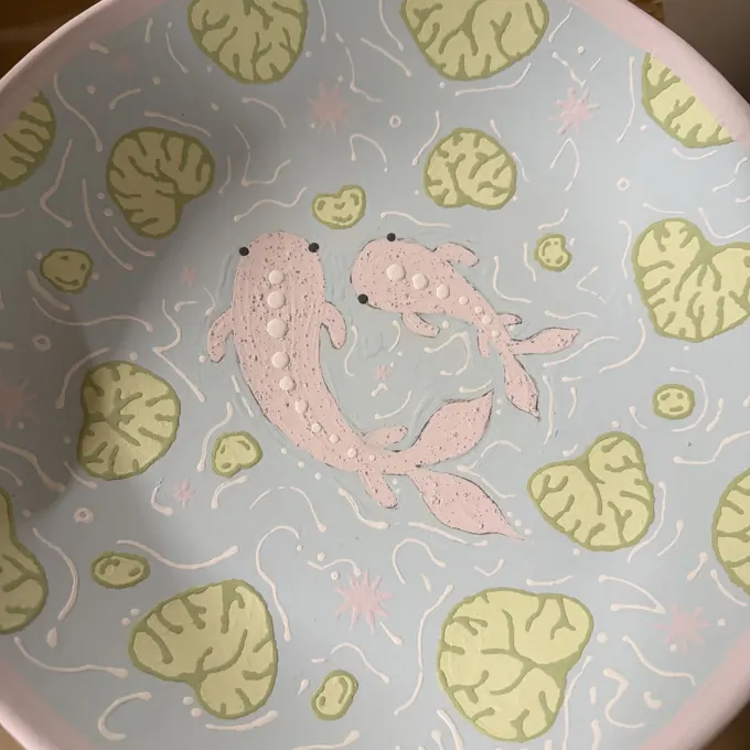 A plate painted with pink koi fish and lily pads