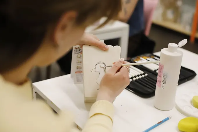 A guest painting a mug at a studio table in the Pictura café