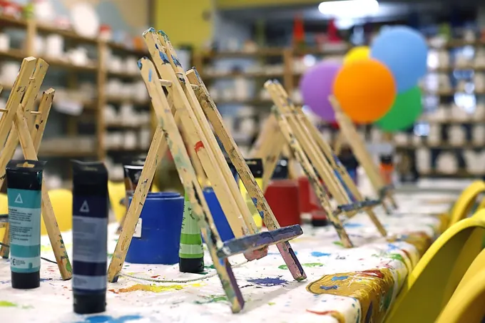 A party table set with mini easels, paints, brushes and balloons in the Pictura studio