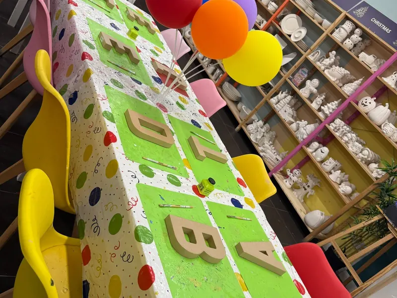 A party table in the Pictura studio laid with decoupage letters, a spotty tablecloth and balloons