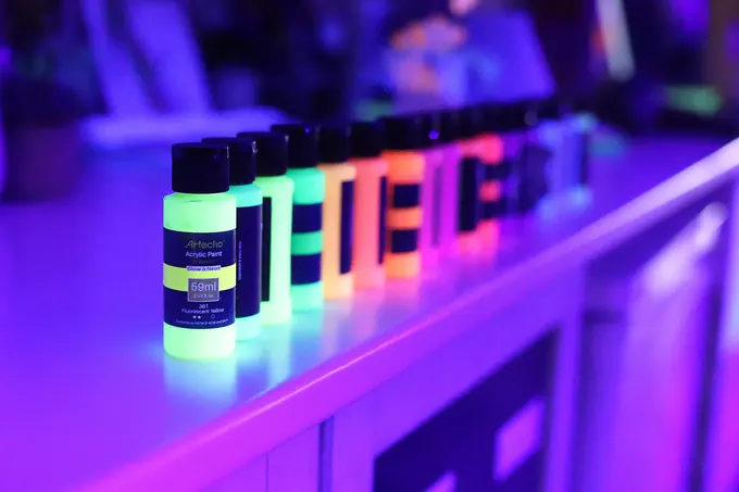 Bottles of glowing neon paint under UV light